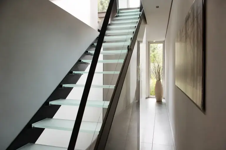 Escalier métallique à marches en verre dans un couloir lumineux